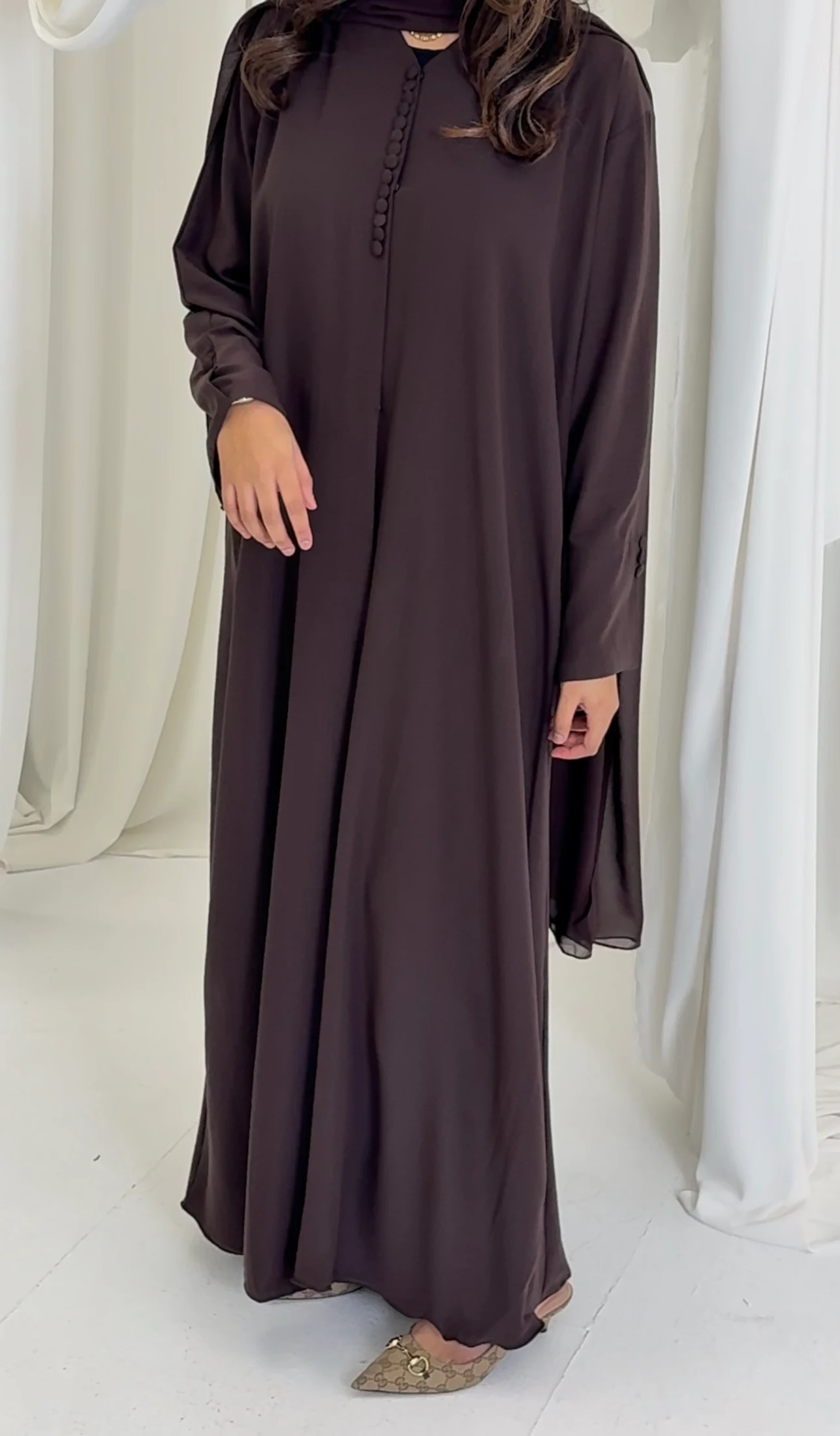 Full-length front view of a brown abaya with covered buttons and wide sleeves.