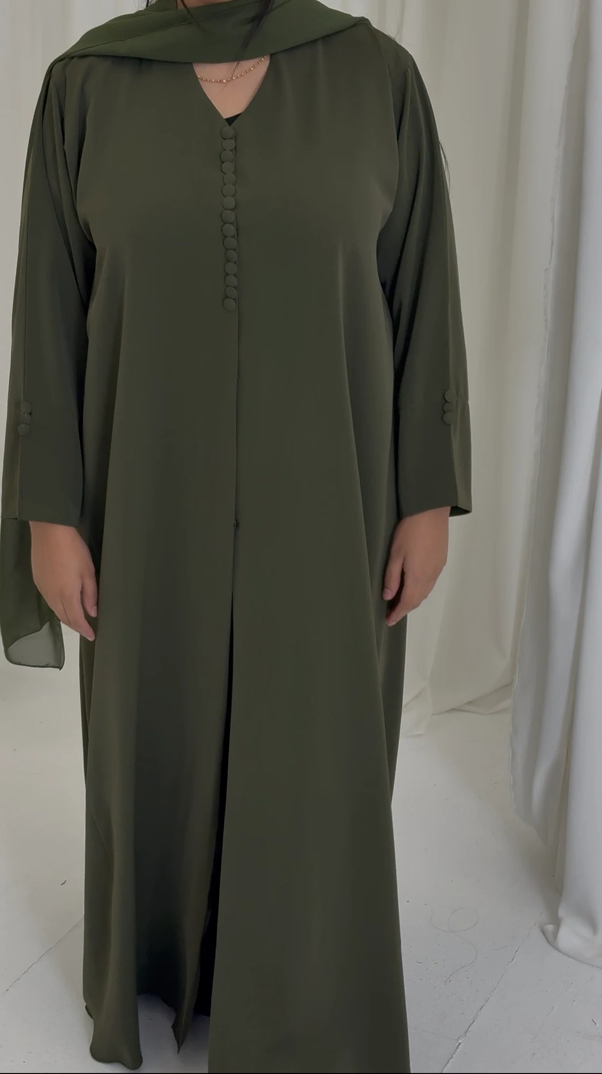 Front view of an olive abaya with covered buttons and wide sleeves.